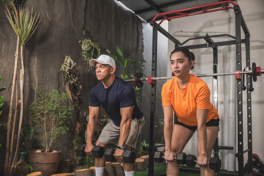 A view of a guy and a girl performing deadlifts