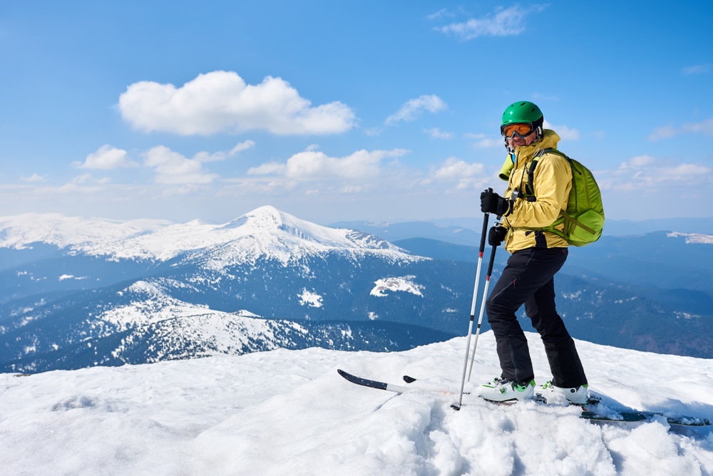 A view of a guy holding ski poles standing in snow