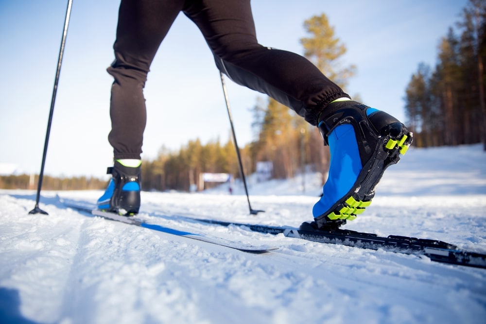 A view of a person wearing ski boots holding sticks in snow