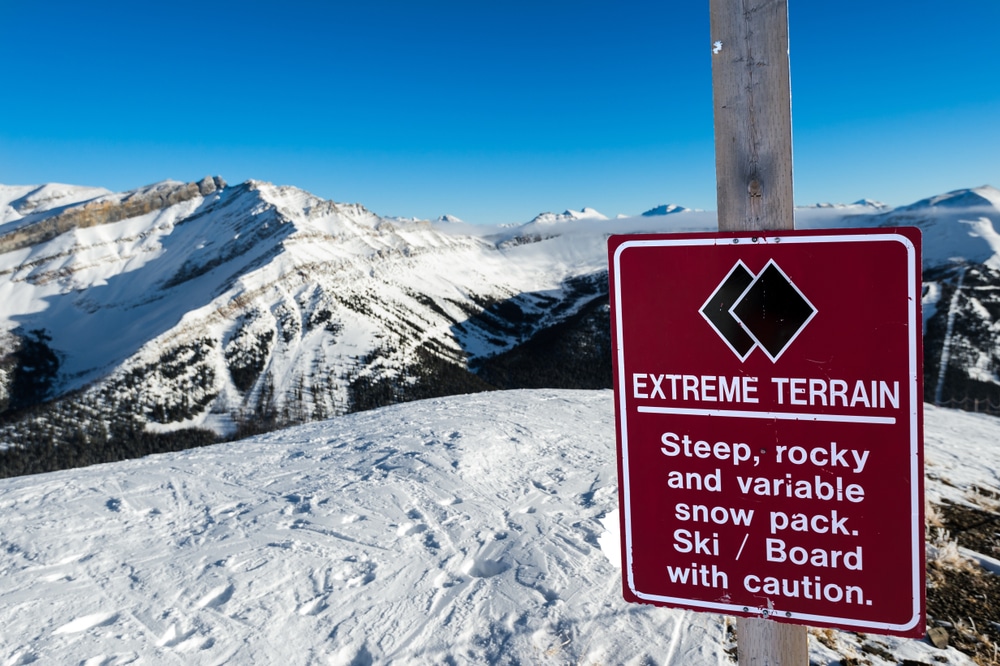 A view of a signboard of a black diamond skiing rocky terrain