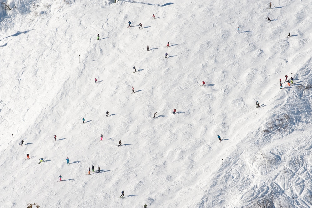 An overhead view of moguls on a ski slope with skiers skiing