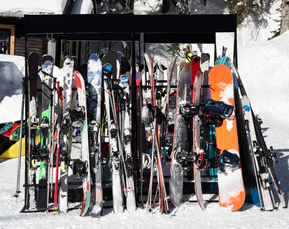 Skis And Snowboards Leaning On Ski Rack Outdoors