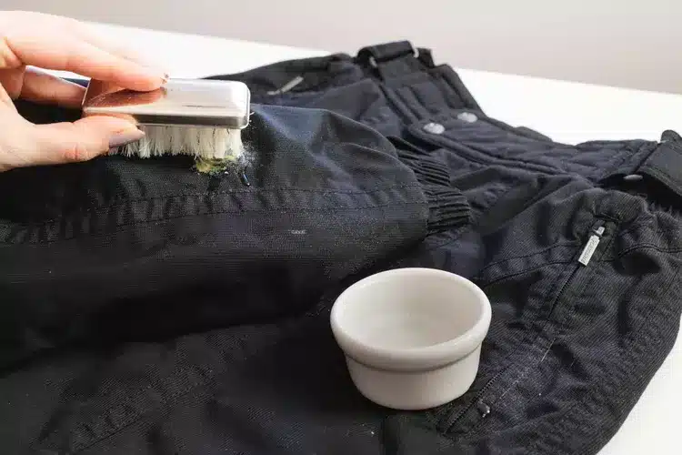 removing visible stains from ski pant using a brush and liquid detergent