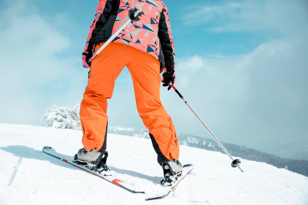 Unrecognizable Skier In Orange Ski Pants Skiing On A Snowy