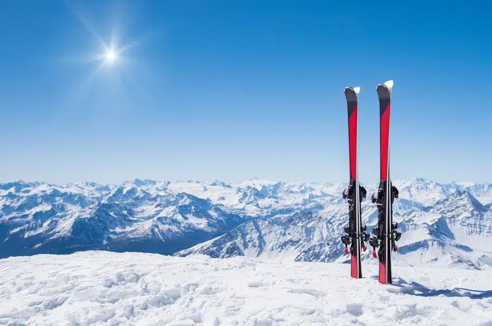 Red skis standing in snow with winter mountains in background