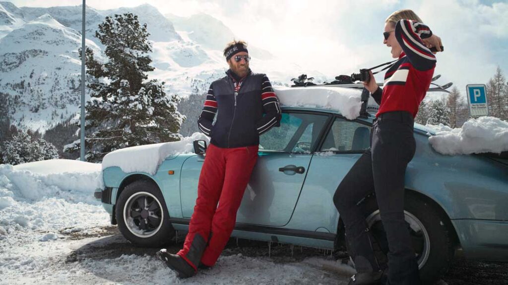 A view of a man and women standing in snow outside a car A view of a man and women standing in snow outside a car