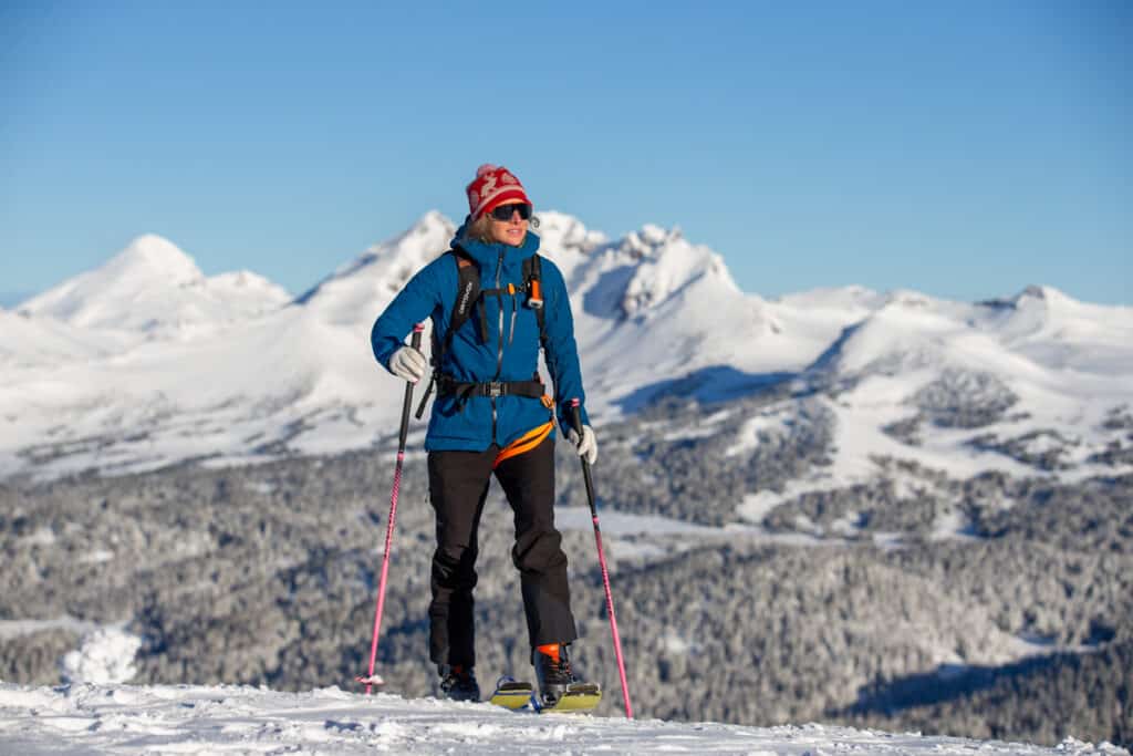 A view of a skier standing with the backdrop of mountains A view of a skier standing with the backdrop of mountains