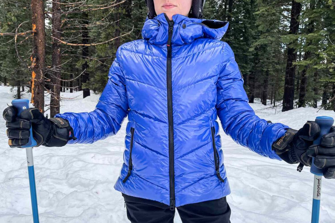 A view of a woman standing in snow wearing a skiing jacket A view of a woman standing in snow wearing a skiing jacket
