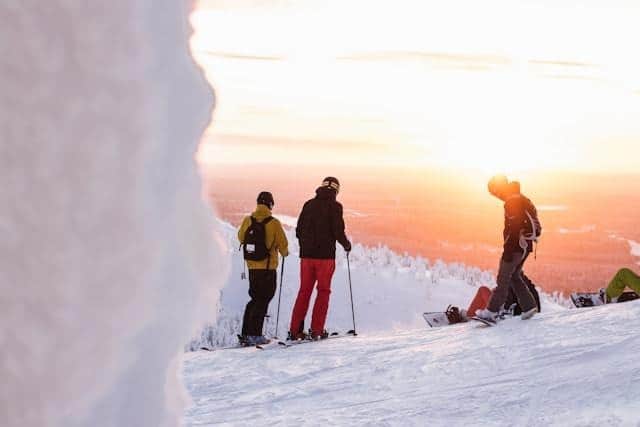 A view of people holding thier skiis and standing in snow with a backdrop of sun A view of people holding thier skiis and standing in snow with a backdrop of sun