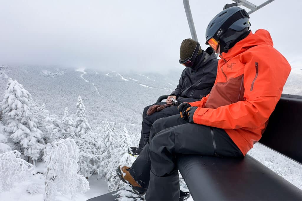 A view of two men wearing skiing jacket sitting on a chairlift A view of two men wearing skiing jacket sitting on a chairlift
