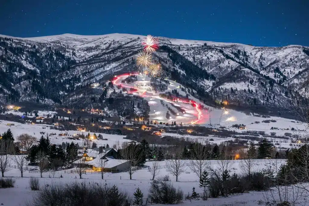 A snowy mountain with lit ski slopes fireworks and glowing skier trails A snowy mountain with lit ski slopes fireworks and glowing skier trails